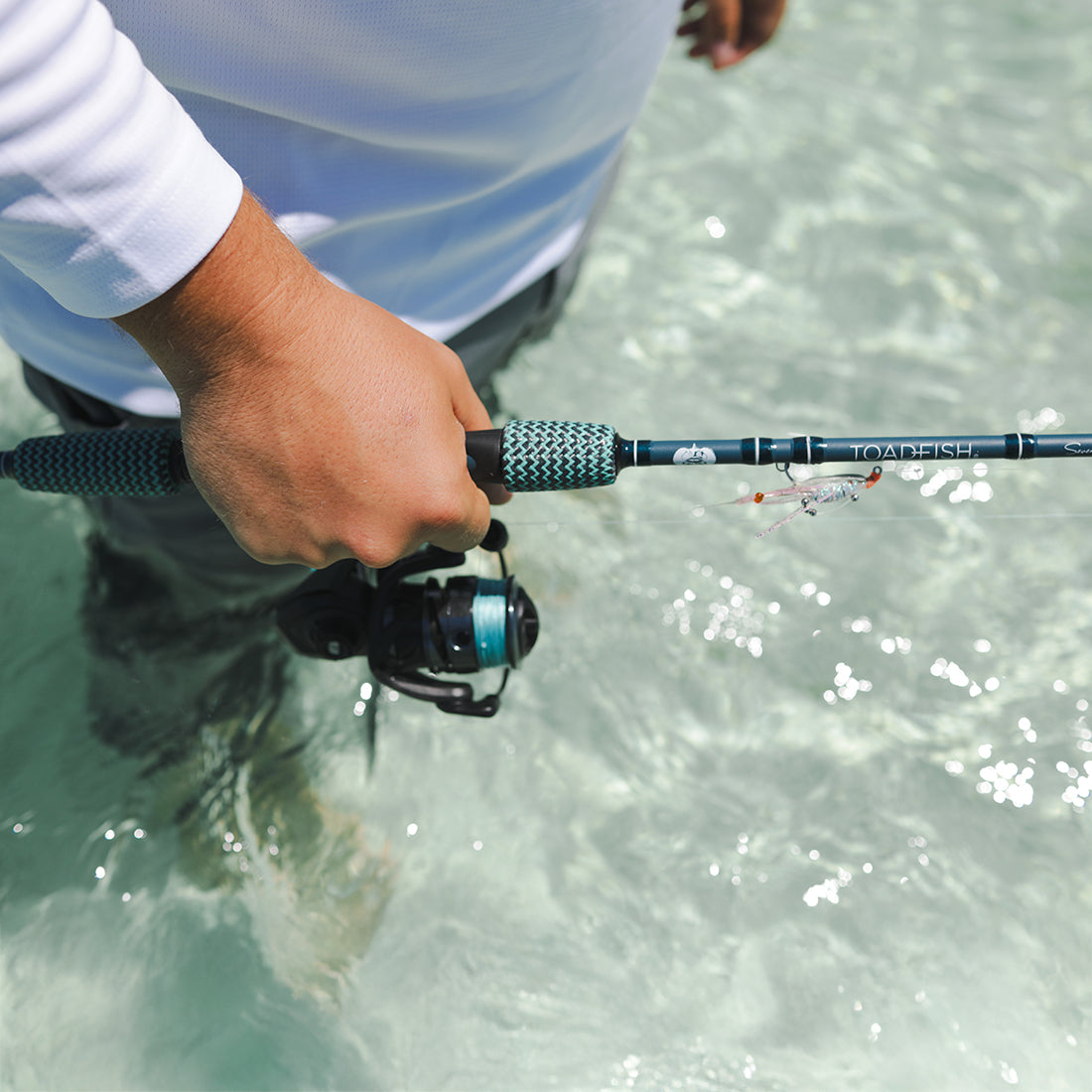 a man is holding a new toadfish flats bastard rod, hes walking in crystal clear water